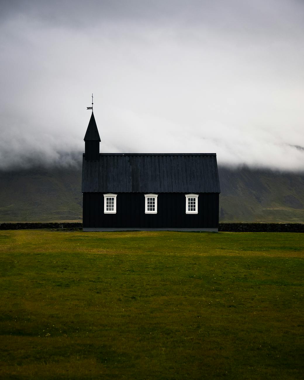 Stark black church against cloudy Icelandic landscape.
