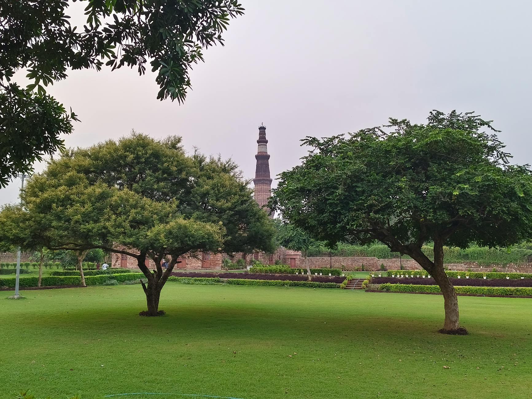 Scenic view of Qutub Minar surrounded by vibrant greenery in a peaceful park setting.