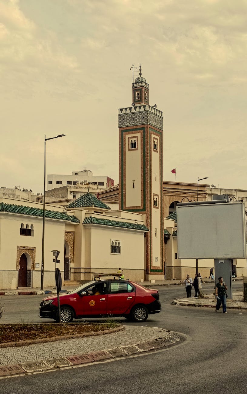 A vibrant city scene with a historic mosque and a red taxi in Morocco.