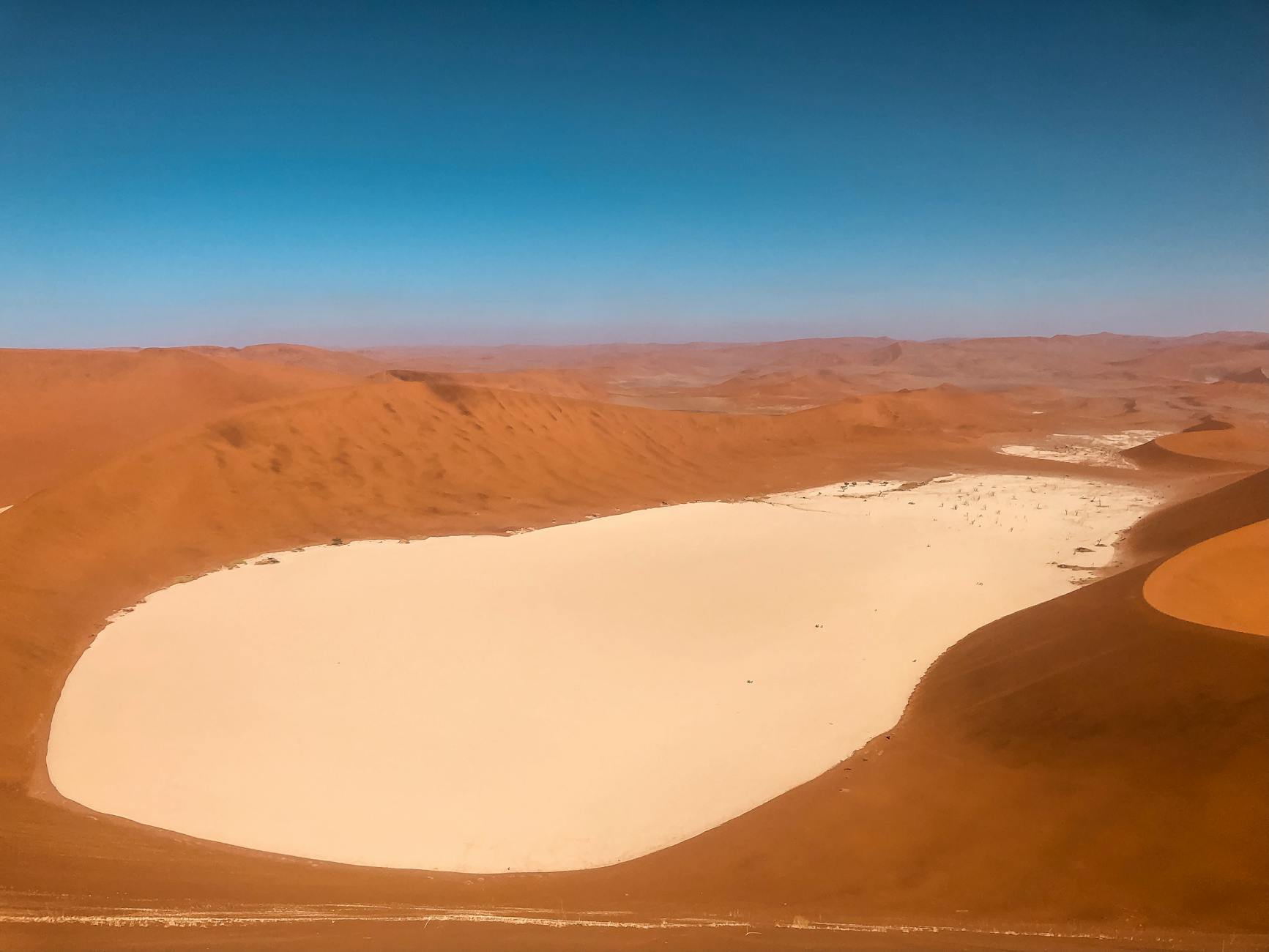 Stunning aerial view of Sossusvlei in Namibia's Namib Desert, featuring vast sand dunes and a white clay pan.